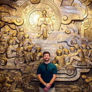 Silviu posing in front of a patriotic mural