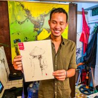 Hoi An - Artist Ha Duong posing with one of his drawing (that we bought!)